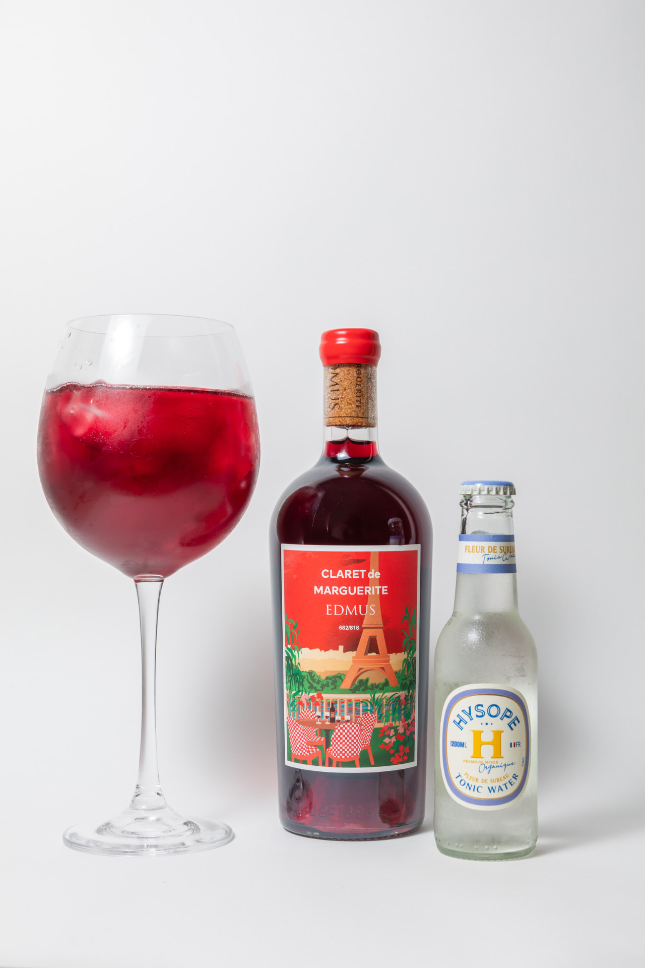 Un verre de Claret Tonic avec glaçons, la bouteille de Claret de Marguerite et un tonic Hysope à la fleur de sureau